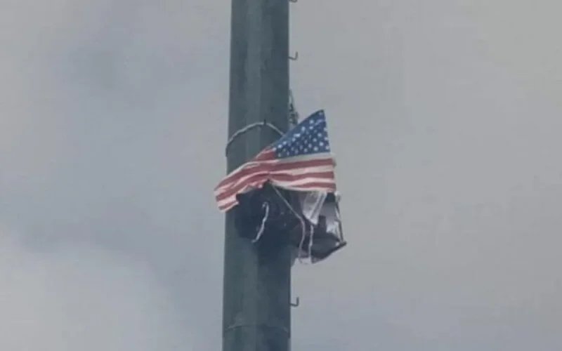Du haut d'un poteau, il menace de se suicider en brandissant le drapeau des USA